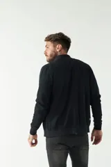 Campera negra de felpa con cierre frontal, bolsillos laterales, puños y logo bordado en el pecho.