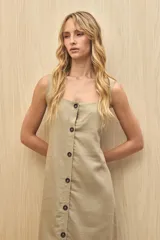 Vestido largo color beige, sin mangas, con escote cuadrado y abotonadura frontal completa. Corte recto con leve abertura en el ruedo.