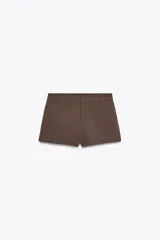 Shorts de tiro bajo color marrón, con bolsillos delanteros, cierre frontal con cremallera y ganchos metálicos.