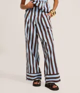 Pantalón de cintura alta, confeccionado en tricolina de algodón, con cierre tradicional, pliegues y rayas verticales en azul claro y marrón.