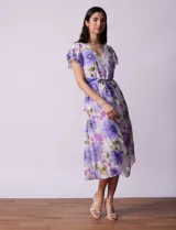Vestido midi de gasa estampada con flores violetas y verdes, escote en V, abertura central con botones, cintura con lazo de ajuste y forro interno a tono.