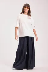 Camiseta blanca de manga corta, corte oversize y cuello redondo. Presenta un pequeño detalle de etiqueta con colores en la manga derecha.