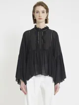 Blusa negra de gasa liviana, con silueta holgada y mangas amplias. Tiene volados frontales, detalles de encaje y cuello alto fruncido, con un estilo romántico y bohemio.