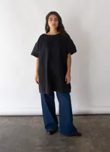Vestido negro de denim de algodón, corte amplio en A y bolsillos laterales.
