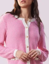 Cárdigan de tejido tweed color rosa y blanco, con escote redondo, abertura frontal con botones metálicos dorados y bolsillos simulados.