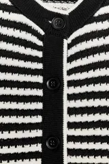 Chaleco de punto con cuello redondo y sisa. Cierre frontal con botones y diseño a rayas horizontales en blanco y negro.