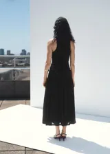 Vestido midi negro sin mangas, con cuello redondo, fruncidos laterales y diseño evasé.