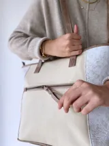Bolso tipo tote bag color beige con laterales estampados y detalles en cuero marrón.