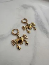 Par de aros dorados con forma de cangrejo colgando de un aro pequeño.