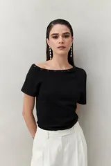 Top tejido azul marino de silueta ajustada con diseño minimalista y escote asimétrico, adornado con pequeños botones metálicos.