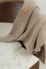 Buzo tejido en hilo de algodón color tostado, de corte holgado, con hombros caídos y diseño de ochos en la parte delantera.