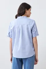 Camisa celeste de manga corta con cuello y ruedo con volados.