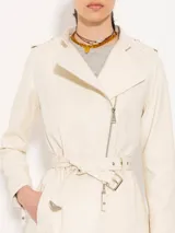 Tapado color crema confeccionado en cuero ovino, con largo hasta arriba de la rodilla. Presenta costadillos, espalda y bajo mangas en complemento al tono que aportan textura. Incluye cinturón en cuero base, bolsillos ojal verticales en el frente y canesú matelaseado. El acceso es mediante cierre metálico al frente.