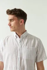 Camisa de manga corta confeccionada en lino y algodón a rayas verticales rojas y azules. Tiene un corte semi slim y logo bordado en el pecho.