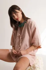 Blusa color crema confeccionada en lino, con mangas cortas, escote en V y lazos frontales.