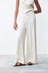 Pantalón palazzo color crudo, de tiro alto y corte holgado.