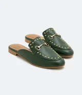 Zapatilla mule color verde oscuro, con puntera redonda, bridón metálico dorado, tachas doradas y suela marrón.