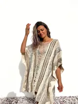 Poncho de tejido rústico color crudo con estampado geométrico en marrón y flecos.