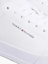 Zapatillas de corte bajo confeccionadas en una mezcla de piel y poliuretano, de color blanco con un panel a contraste en el talón. Presentan cierre de cordones, suela de goma y el logo de Tommy Hilfiger en el lateral.