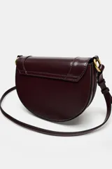 Bolso de hombro ovalado color negro, con asa de doble tira redonda con detalles metalizados dorados. Cierre imantado y asa de bandolera extraíble con tejido a contraste. Bolso interior con cierre mediante cremallera metálica.