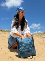 Bolso tipo shopper color beige con diseño acolchado geométrico y correa de hombro negra.