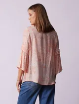 Blusa de gasa estampada color salmón con flores blancas, marca Ruby Rd. Cuello a la base, escote en V y abertura central con botones. Delantera con plisados. Largo de manga ¾ con terminación amplia.