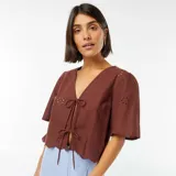 Blusa marrón con escote en V, mangas cortas y lazos para atar en el frente.