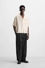 Camisa color crema de manga corta con cuello bowling, corte relaxed fit y bolsillo de parche en el pecho.