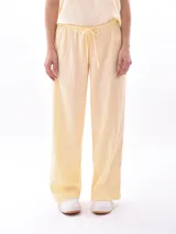Pantalón de lino color crudo, de corte recto y tiro alto, con cintura elástica y lazo ajustable.