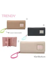 Billetera color beige con cierre de solapa y broche a presión. Presenta un aplique con la palabra 'TRENDY' repetida en rosa y verde. Incluye un llavero de muñeca con cordón verde y rosa.