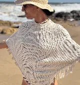 Poncho tejido en hilo de algodón con lurex, color crudo, con flecos en el ruedo.