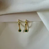 Aros dorados tipo argolla con dije colgante de cristal verde.