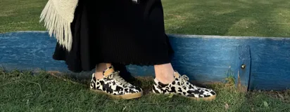 Zapatillas bajas con estampado animal print de vaca en blanco y negro, con cordones marrones y suela color caramelo.