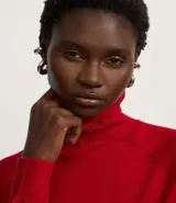 Blusa de punto color blanco, con cuello alto, manga larga y diseño liso.