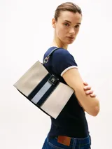 Cartera tote de lona color beige con rayas verticales azul marino y blanco. Tiene asa superior, correa ajustable y extraíble, cierre magnético y múltiples compartimentos interiores.