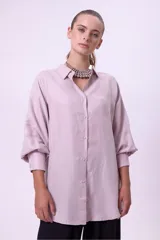 Camisa de cupro color lila de calce oversize, con cuello camisero y botones frontales a tono. Posee mangas largas con volumen y puños definidos.