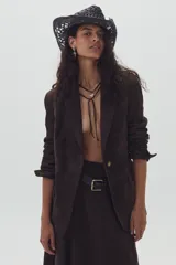 Blazer marrón de gamuza de cabra con apliques tribales al tono en el frente y en las mangas. Tiene bolsillos frontales y uno interno.