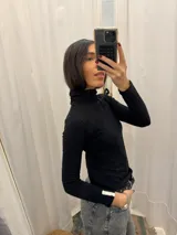 Polera blanca de algodón con cuello alto y mangas largas.