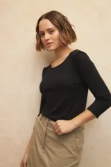 Remera de manga tres cuartos, cuello a la base y costuras marcadas en los hombros, fabricada en textil elastizado.