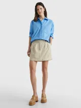 Camisa celeste de popelín de algodón orgánico, corte oversize con hombros caídos, cuello inglés, bolsillo de parche en el pecho y logo bordado en la manga.