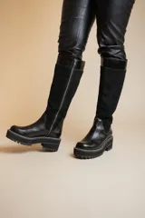 Bota alta de cuero negro con caña de gamuza y suela track.