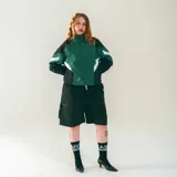 Campera deportiva de nylon liviano, con calce relajado y estructura clásica. Presenta bloques de color verde oscuro, negro y blanco en el frente y mangas. Tiene cuello alto con cierre y un micrográfico en el pecho.