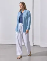 Camisa de jean celeste con flecos en el ruedo, de mangas largas y corte recto.