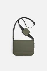 Bandolera color verde militar con acabado engomado y textura acanalada. Tiene un compartimento principal con cierre de solapa y botón a presión, un bolsillo interior con cremallera y un monedero cuadrado extraíble en la correa.
