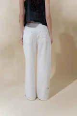 Pantalón de lino rústico color blanco, de calce recto y tiro medio. Tiene bolsillos delanteros y traseros.