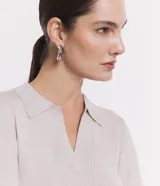 Blusa de manga larga, color beige claro con brillo sutil, tejido acanalado y cuello polo con escote en V.