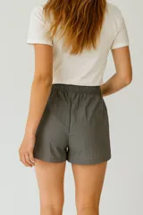 Short gris de poliéster, holgado y de calce medio, con cintura elástica ajustable con cordón.