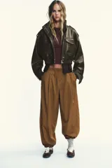 Pantalón de tiro medio color marrón claro, con cintura elástica, bolsillos laterales ocultos y puños elásticos.