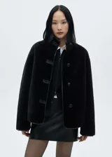 Chaqueta negra de efecto pelo con cuello alto, diseño oversize, manga larga, cierre de botón en la parte delantera y dos bolsillos delanteros.