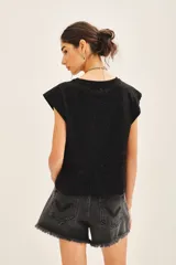 Remera negra de jersey con glitter, detalles en tela base en el frente y medallita marcaria en la espalda.